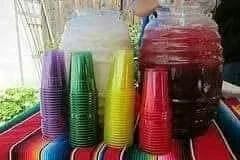 Recipientes de aguas frescas y vasos de colores